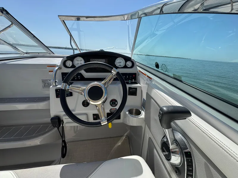Slide: The Image of 2020 Regal 28 Express boat cockpit with steering wheel and control panel, overlooking calm waters. - 10
