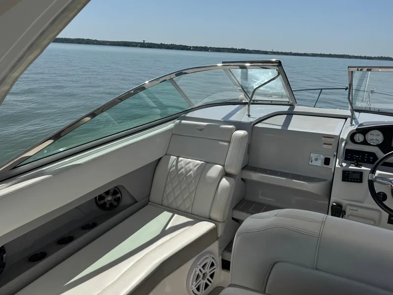 Slide: The Image of 2020 Regal 28 Express boat interior with luxurious seating and dashboard, on calm water. - 16