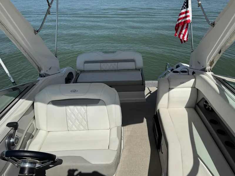 Slide: The Image of 2020 Regal 28 Express boat interior with white seating and American flag on calm water. - 17