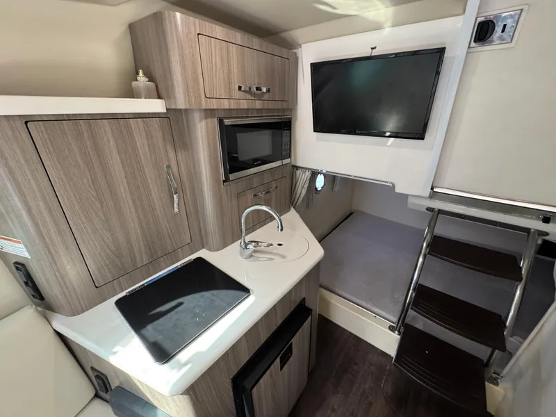 Slide: The Image of 2020 Regal 28 Express boat interior with kitchenette, TV, and stairs to cabin. - 30