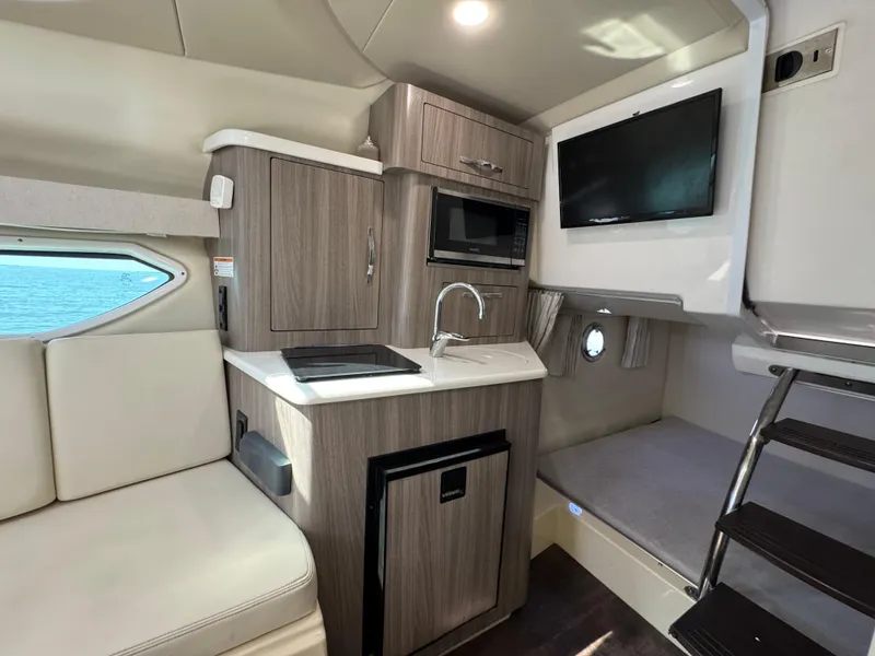 Slide: The Image of 2020 Regal 28 Express cabin interior with kitchenette, seating, and TV. - 32