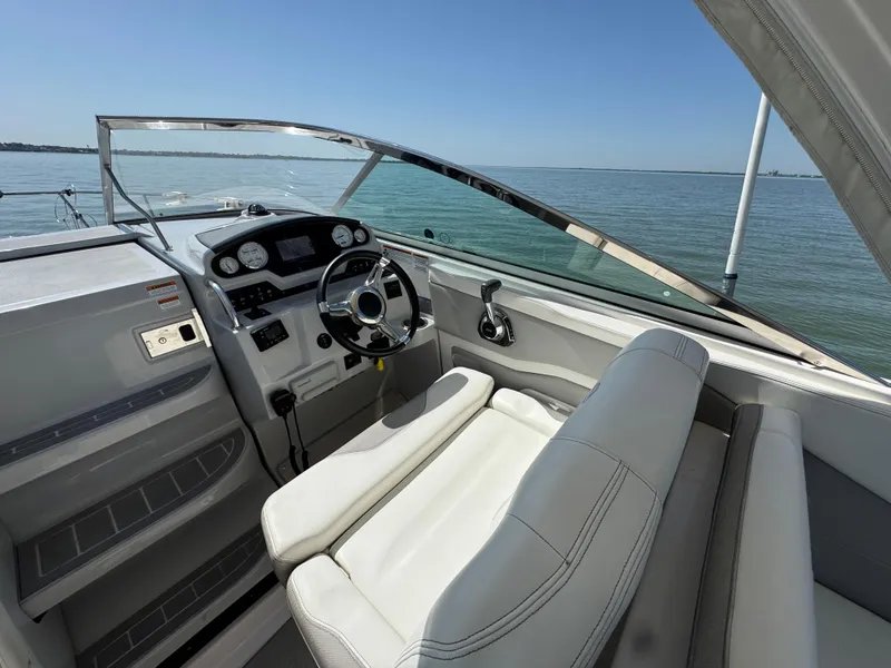 Slide: The Image of 2020 Regal 28 Express boat interior with steering wheel, dashboard, and seating, overlooking calm waters. - 9