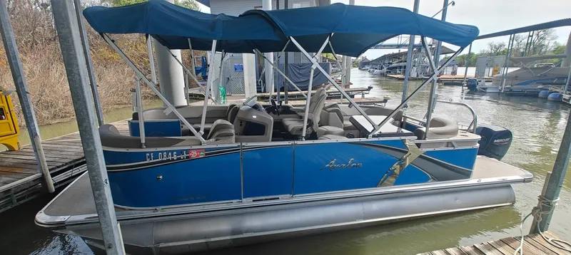 Slide: The Image of 2023 Avalon LSZ Entertainer pontoon boat with blue canopy docked at marina. - 1