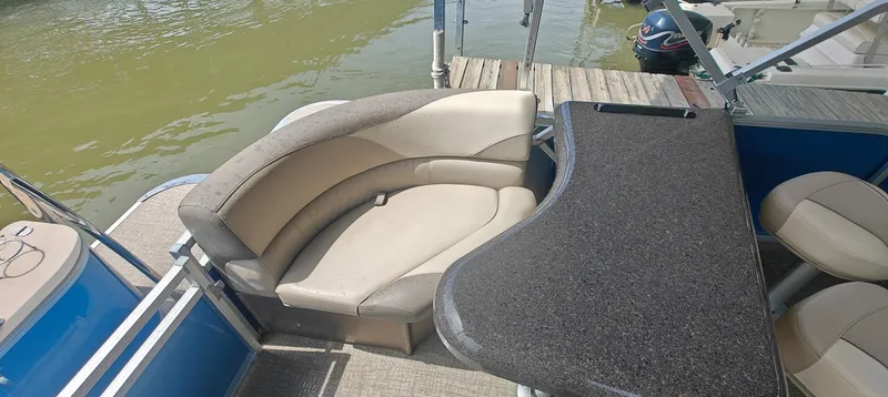 Slide: The Image of 2023 Avalon LSZ Entertainer boat interior with seating and table, docked by the water. - 12