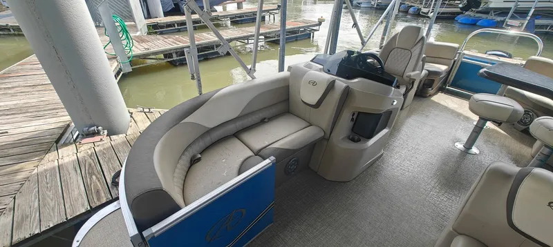 Slide: The Image of 2023 Avalon LSZ Entertainer pontoon boat interior with seating and helm, docked at marina. - 6