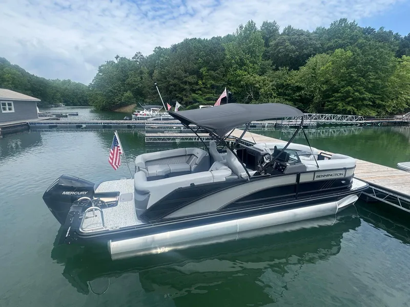 Slide: The Image of 2025 Bennington 22MFB pontoon boat docked on a serene lake. - 14