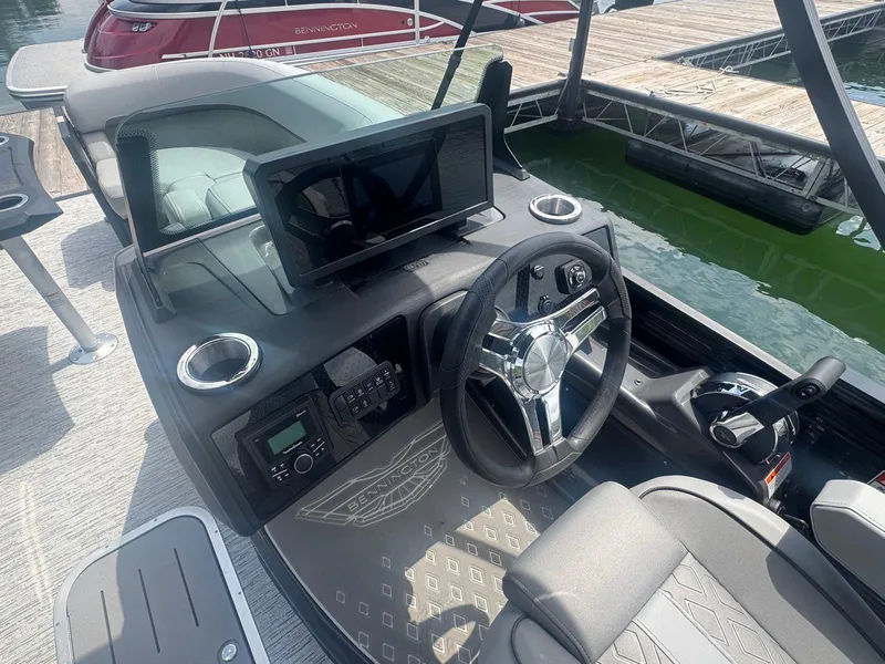 Slide: The Image of 2025 Bennington 22MFB boat dashboard with steering wheel and control panel at marina. - 20