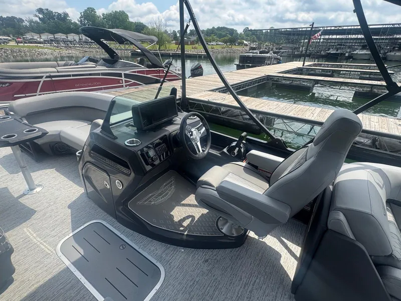 Slide: The Image of 2025 Bennington 22MFB boat interior with modern helm and seating at a marina. - 25