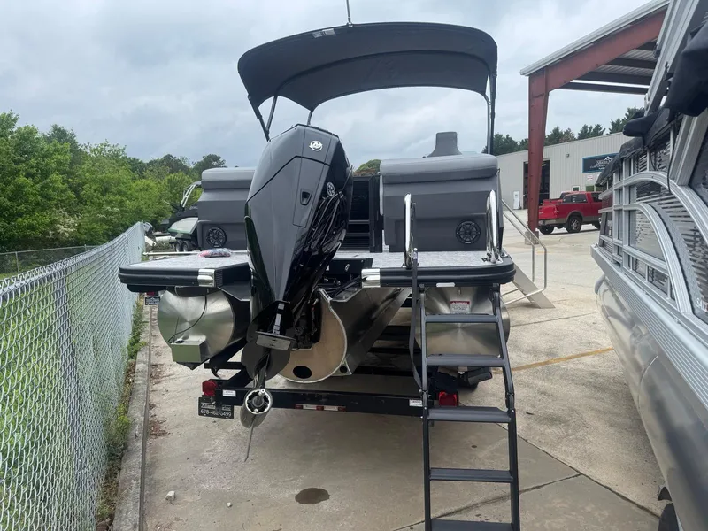 Slide: The Image of 2025 Bennington 22MFB pontoon boat with outboard motor and ladder, parked outdoors. - 3