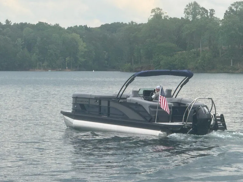 Slide: The Image of 2025 Bennington 24MFB pontoon boat cruising on a lake with American flag. - 16