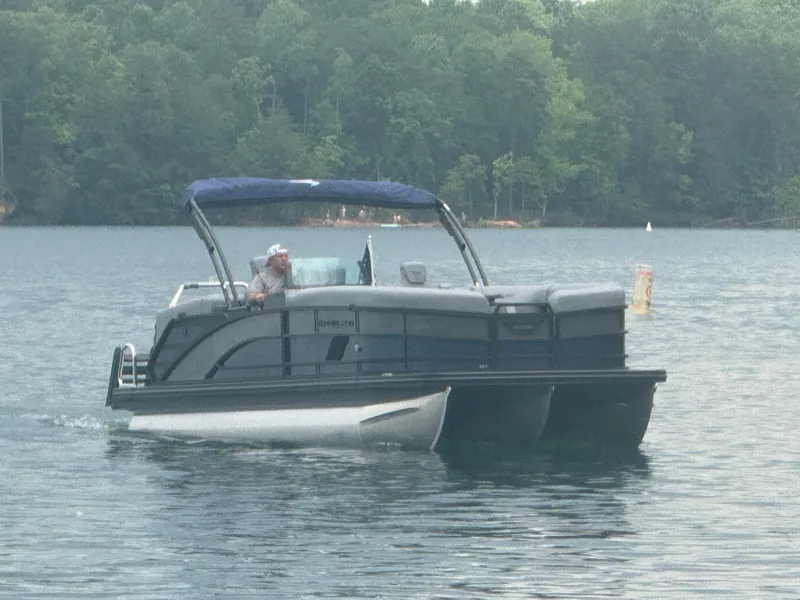 Slide: The Image of 2025 Bennington 24MFB pontoon boat cruising on a serene lake. - 19