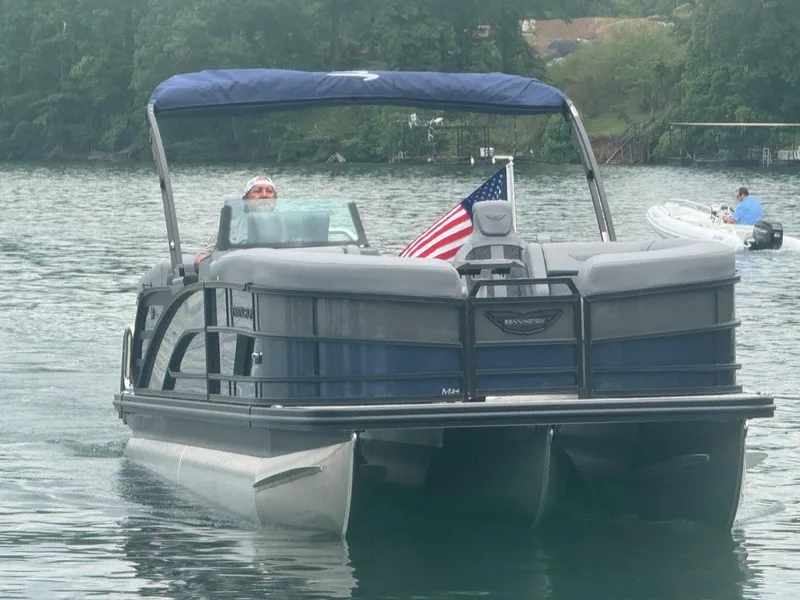 Slide: The Image of 2025 Bennington 24MFB pontoon boat on a lake with American flag. - 20