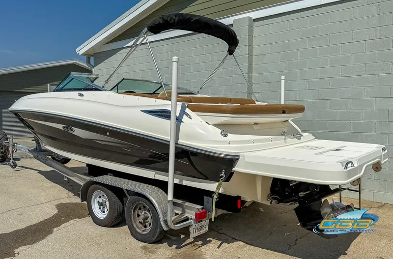 Slide: The Image of 2015 Sea Ray 240 Sundeck boat on trailer, parked outdoors near a building. - 2