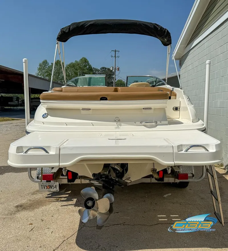 Slide: The Image of 2015 Sea Ray 240 Sundeck boat, rear view, parked outdoors, showcasing propeller and seating area. - 27