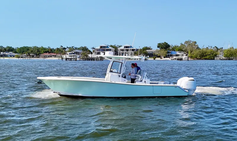 Slide: The Image of 2020 Sportsman Open 282 Center Console boat cruising on a sunny day near waterfront homes. - 4