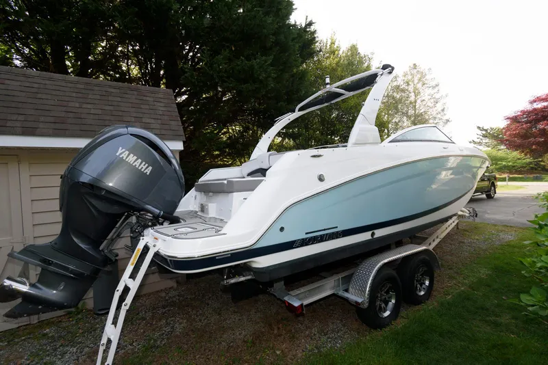 Slide: The Image of 2022 Four Winns HD5 OB boat on trailer with Yamaha outboard motor, parked near trees. - 2