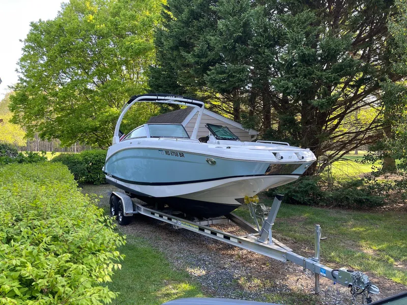 Slide: The Image of 2022 Four Winns HD5 OB boat on trailer, parked in a lush green garden setting. - 3