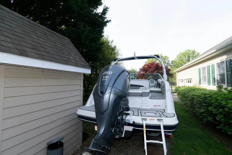 Slide: The Image of 2022 Four Winns HD5 OB boat with outboard motor, parked beside a house. - 4