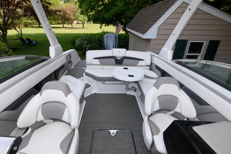 Slide: The Image of 2022 Four Winns HD5 OB boat interior with white seating and table, parked near a house. - 6