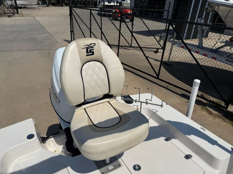 Slide: The Image of 2021 Carolina Skiff 192 JLS boat seat with beige upholstery and logo, docked near a fence. - 28