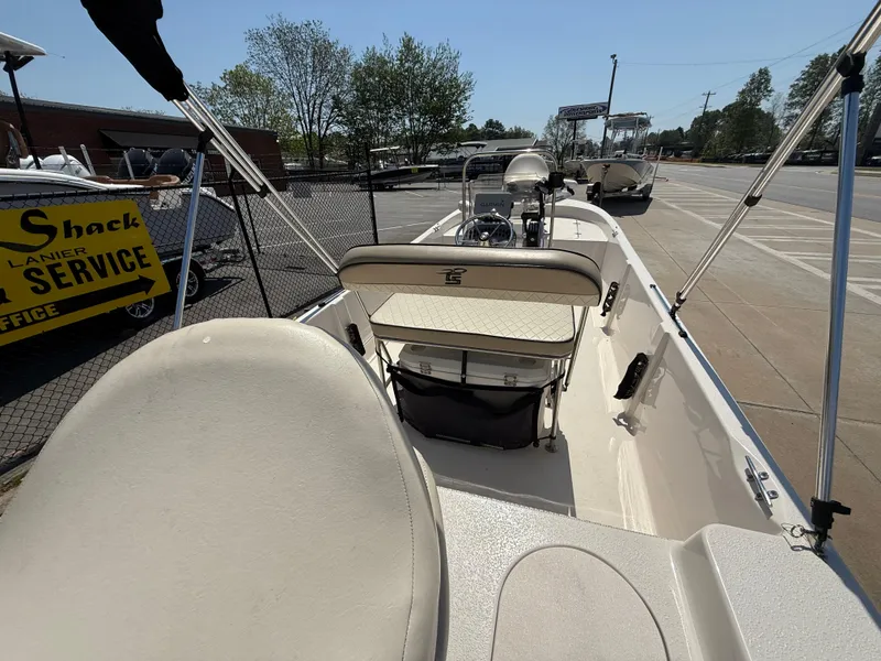 Slide: The Image of 2021 Carolina Skiff 192 JLS boat interior with seating and console, parked outdoors. - 34