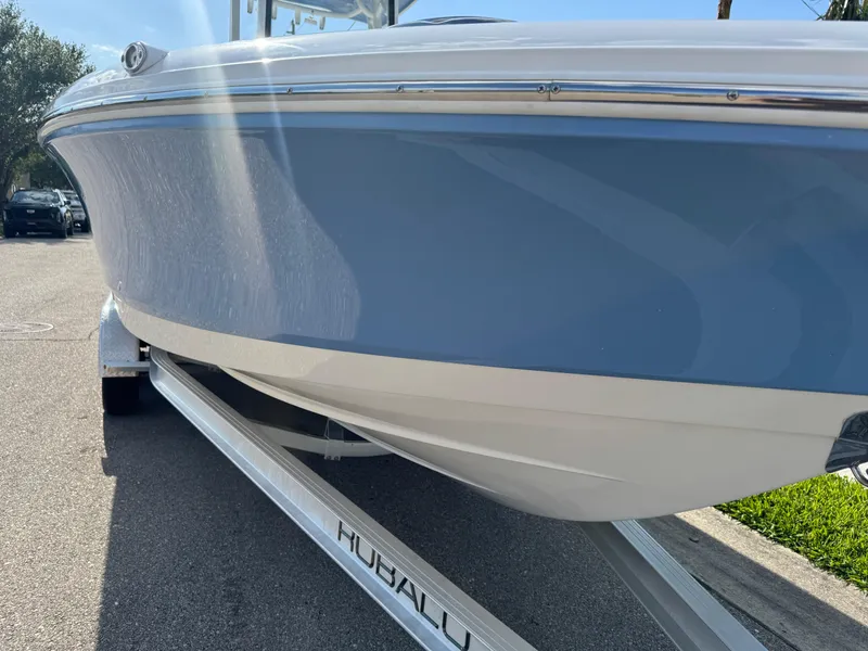 Slide: The Image of 2023 Robalo 246 Cayman boat on trailer, blue and white hull, sunny day. - 25