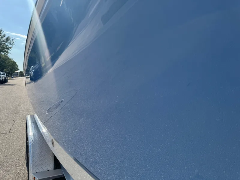 Slide: The Image of 2023 Robalo 246 Cayman boat hull, glossy blue finish, parked on a trailer. - 26