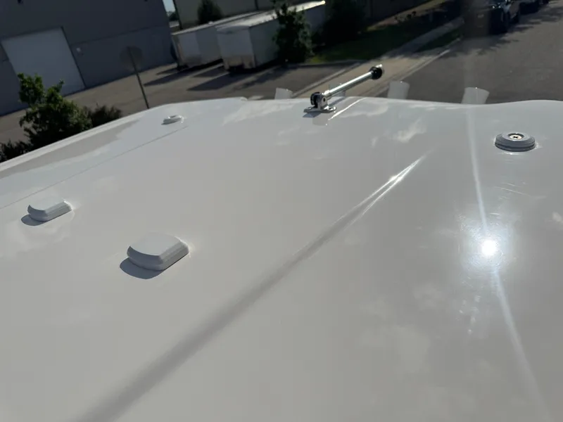 Slide: The Image of 2023 Robalo 246 Cayman boat deck with sunlight reflection and urban background. - 44