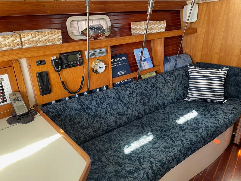 Slide: The Image of 1997 Catalina 320 yacht interior with blue sofa, striped pillow, and wooden accents. - 10