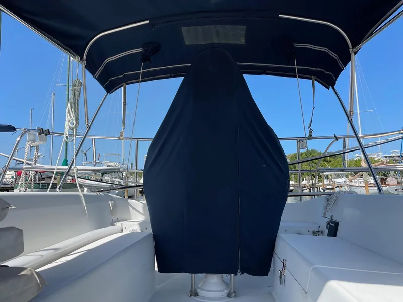 Slide: The Image of 1997 Catalina 320 sailboat cockpit with covered helm, marina background, and blue canopy. - 13