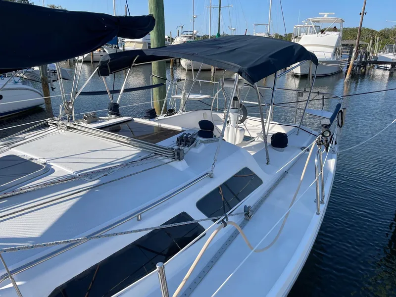 Slide: The Image of 1997 Catalina 320 sailboat docked in marina, featuring blue canopy and sleek design. - 14