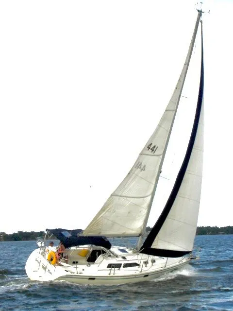 Slide: The Image of 1997 Catalina 320 sailboat navigating on open water with full sails. - 21