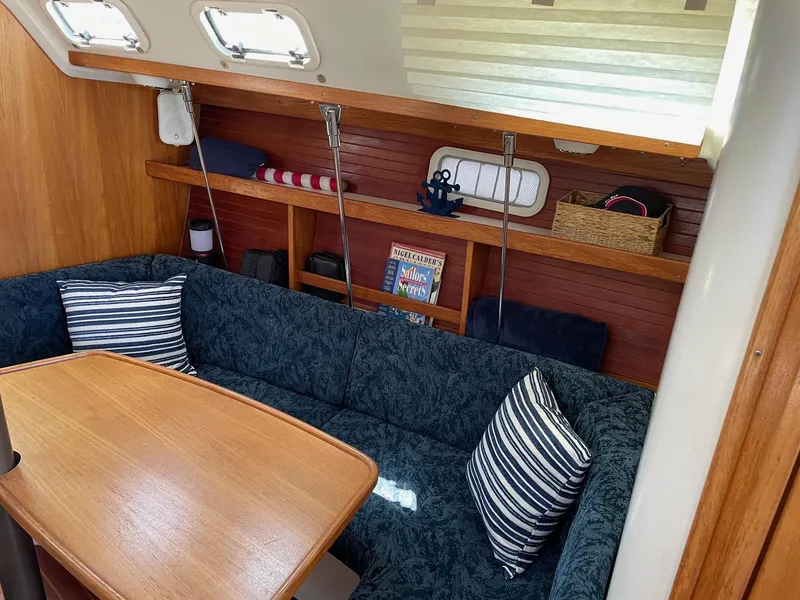 Slide: The Image of Cozy interior of 1997 Catalina 320 sailboat with blue seating and wooden table. - 23