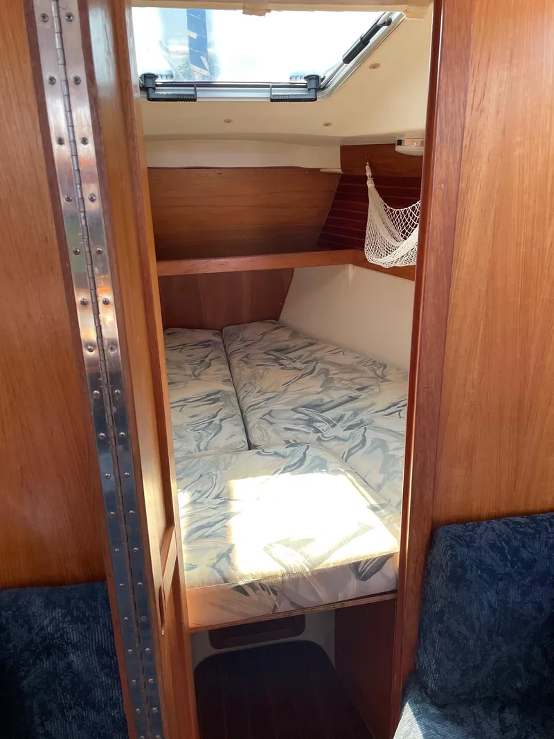 Slide: The Image of 1997 Catalina 320 sailboat cabin with cozy bed and wooden interior. - 24