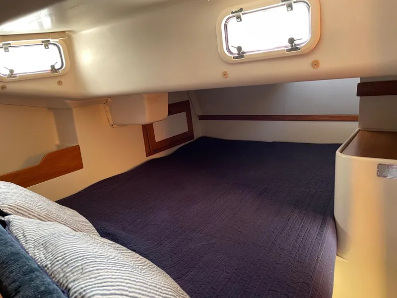 Slide: The Image of Interior cabin of a 1997 Catalina 320 sailboat with cozy bedding and portholes. - 27