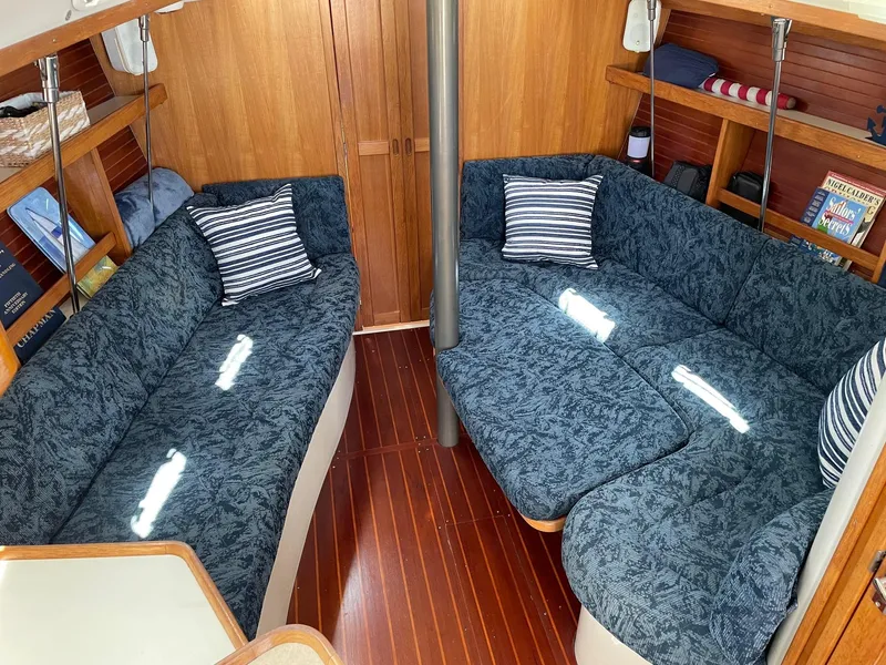 Slide: The Image of Interior of a 1997 Catalina 320 sailboat with blue cushioned seating and wooden flooring. - 4