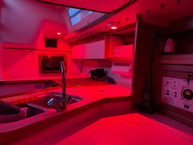 Slide: The Image of Interior of a 1997 Catalina 320 sailboat galley, illuminated by red lighting. - 40