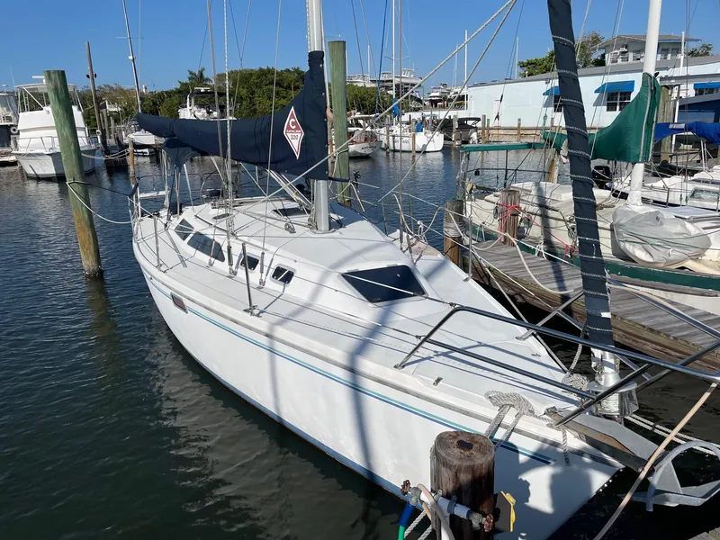Slide: The Image of 1997 Catalina 320 sailboat docked in a marina, surrounded by other boats. - 41