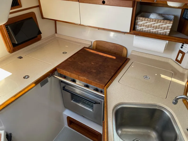 Slide: The Image of 1997 Catalina 320 yacht kitchen with stove, sink, and wooden countertops. - 5
