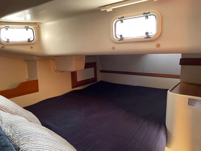 Slide: The Image of Cozy cabin interior of a 1997 Catalina 320 sailboat with portholes and bedding. - 6