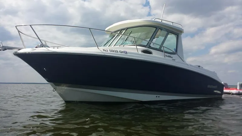 Slide: The Image of 2006 Wellcraft 252 Coastal boat on water under cloudy sky. - 0