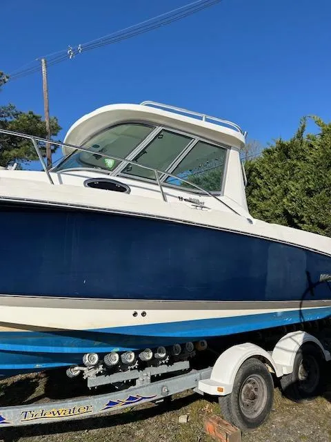Slide: The Image of 2006 Wellcraft 252 Coastal boat on trailer, blue and white design, clear sky background. - 3