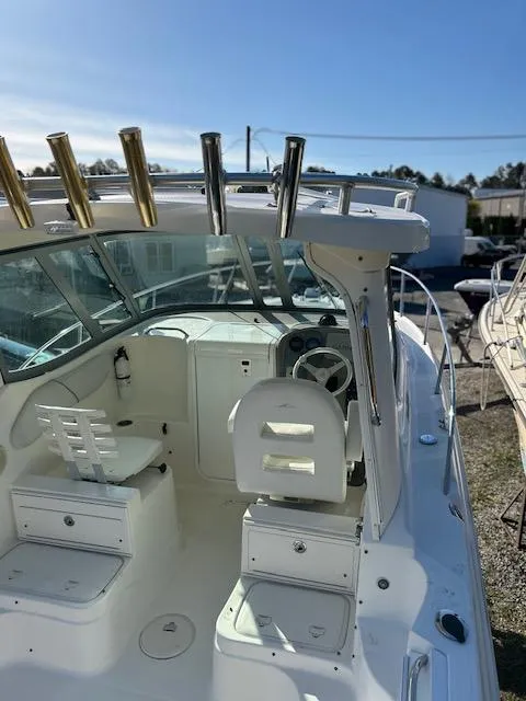Slide: The Image of 2006 Wellcraft 252 Coastal boat interior with helm, seating, and rod holders under clear blue sky. - 7