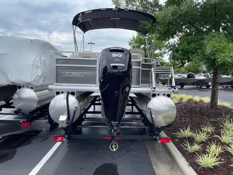 Slide: The Image of 2025 Sun Tracker Fishin' Barge 20 DLX pontoon boat with Mercury 90 engine, parked outdoors. - 2