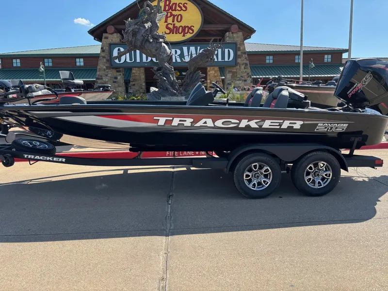 The Image of 2025 Tracker Savage 215 boat on trailer, parked outdoors with trees in background. - 0