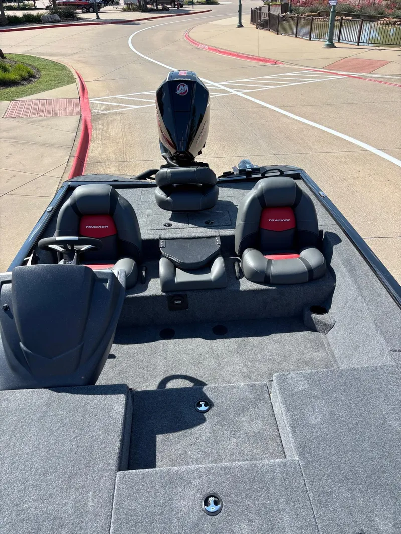 Slide: The Image of 2025 Tracker Savage 215 boat with dual seats and outboard motor, parked on a paved area. - 5
