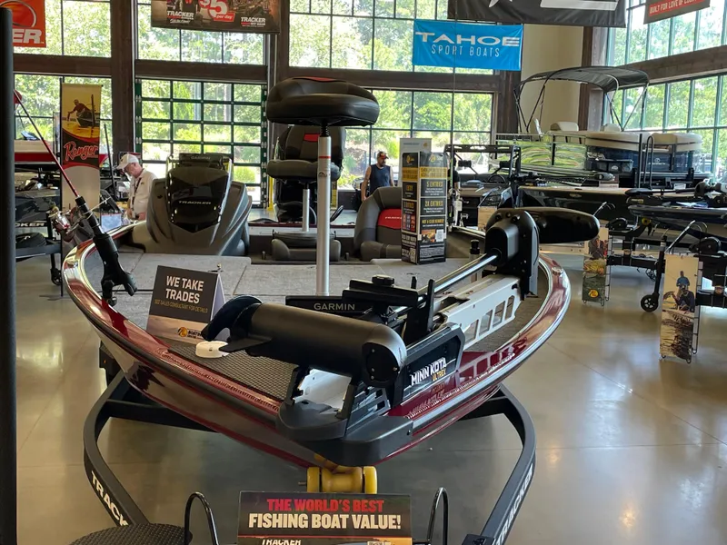Slide: The Image of 2025 Tracker Savage 215 fishing boat displayed in showroom with trade-in offer sign. - 2