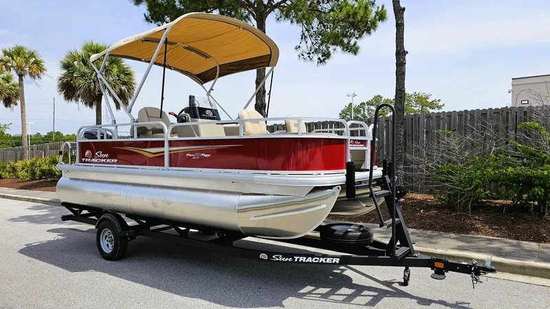 Slide: The Image of 2025 Sun Tracker Bass Buggy 18 DLX pontoon boat on trailer, parked outdoors. - 3