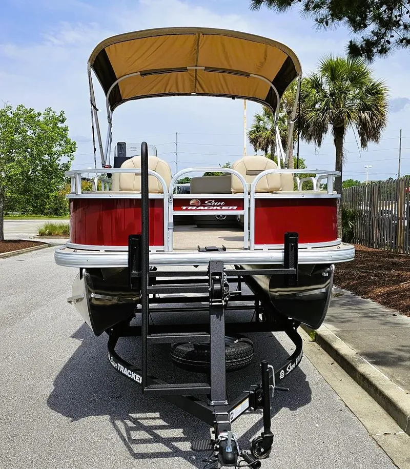 Slide: The Image of 2025 Sun Tracker Bass Buggy 18 DLX pontoon boat on trailer, parked outdoors. - 6