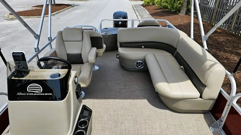 Slide: The Image of 2025 Sun Tracker Bass Buggy 18 DLX pontoon boat interior with beige seating and steering console. - 7